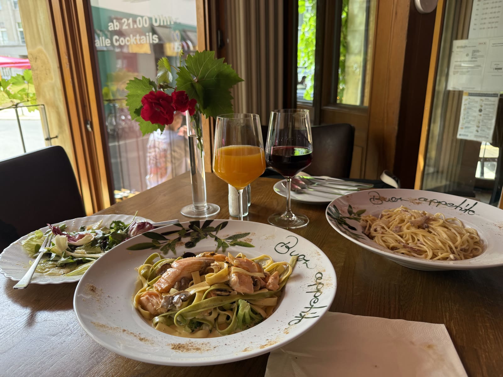 Tagliatelle Salmon mit Lachs und Broccoli am Fenstertisch, daneben Salat und Getränke